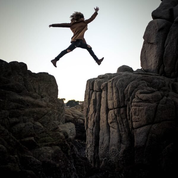 person jumping on big rock under gray and white sky during daytime; High Yields Signal Impending Doom; dividend investing