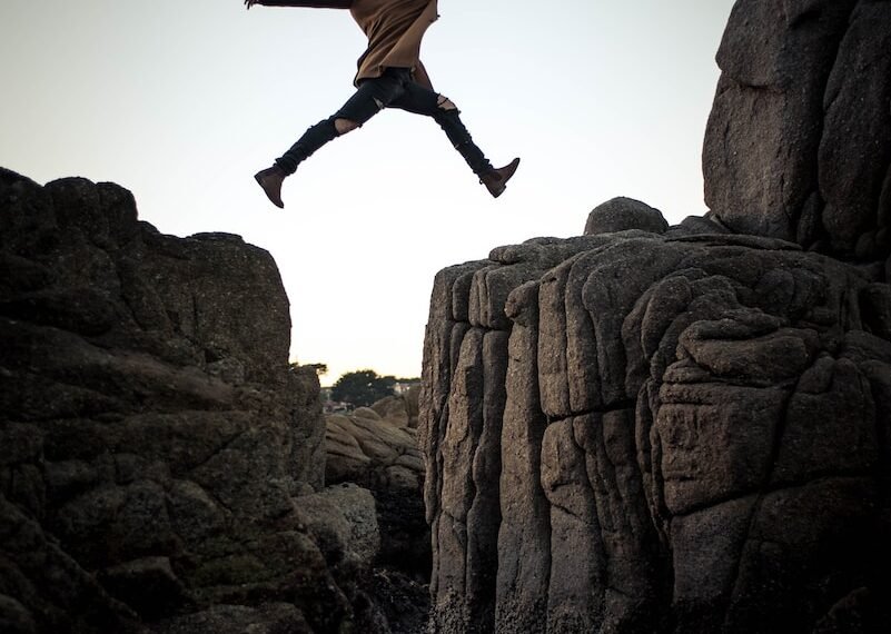 person jumping on big rock under gray and white sky during daytime; High Yields Signal Impending Doom; dividend investing