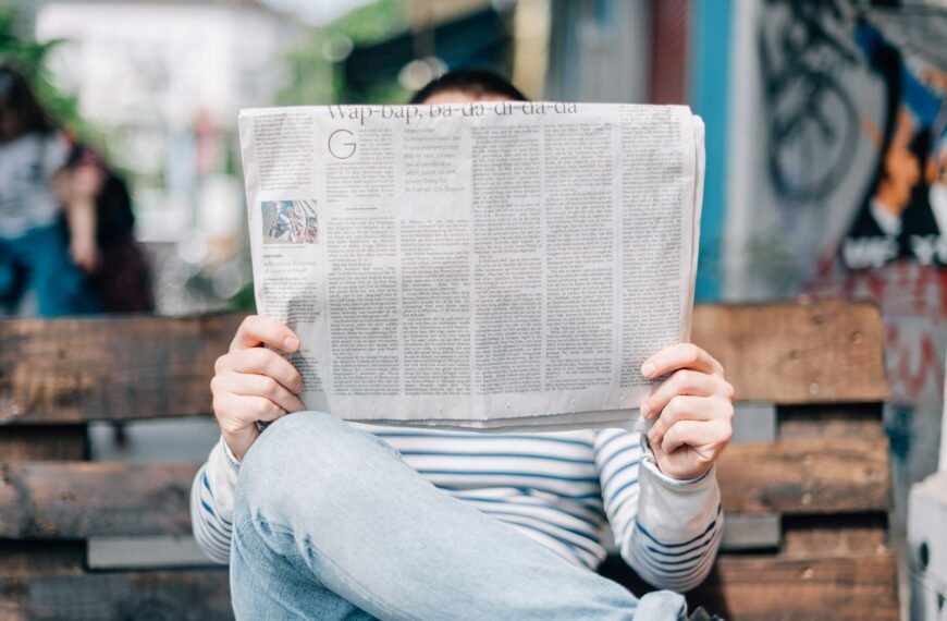 man sitting on bench reading newspaper